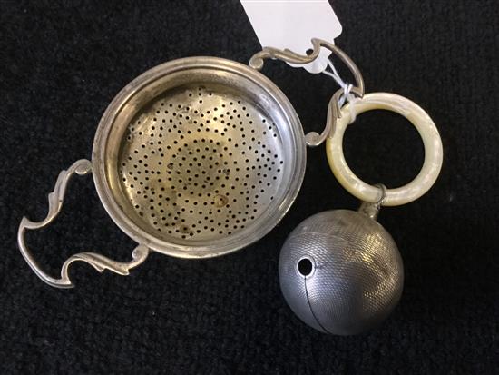 A silver tea strainer and a babys rattle